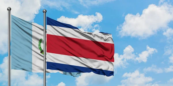 Bandera de Guatemala y Costa Rica ondeando en el viento contra el cielo azul nublado blanco juntos. Concepto diplomático, relaciones internacionales . — Foto de Stock