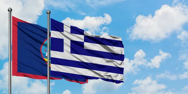 Guam e a bandeira da Grécia agitando no vento contra o céu azul nublado branco juntos. Conceito de diplomacia, relações internacionais . — Fotografia de Stock