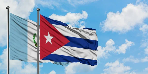 Bandera de Guatemala y Cuba ondeando en el viento contra el cielo azul nublado blanco juntos. Concepto diplomático, relaciones internacionales . — Foto de Stock