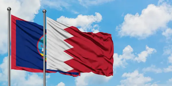 Guam en Bahrein vlag zwaaien in de wind tegen witte bewolkte blauwe hemel samen. Diplomatie concept, internationale betrekkingen. — Stockfoto