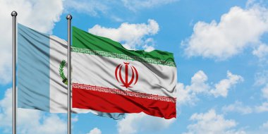 Guatemala ve İran bayrağı birlikte beyaz bulutlu mavi gökyüzüne karşı rüzgarsal sallayarak. Diplomasi kavramı, uluslararası ilişkiler.