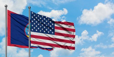Guam ve Amerika Birleşik Devletleri bayrağı birlikte beyaz bulutlu mavi gökyüzüne karşı rüzgarda sallayarak. Diplomasi kavramı, uluslararası ilişkiler.