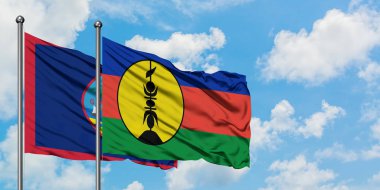 Guam ve Yeni Kaledonya bayrağı birlikte beyaz bulutlu mavi gökyüzüne karşı rüzgarda sallayarak. Diplomasi kavramı, uluslararası ilişkiler.