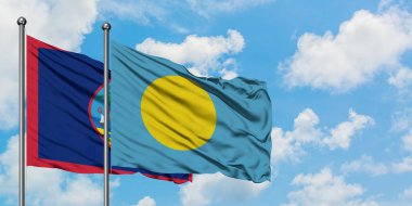 Guam ve Palau bayrağı birlikte beyaz bulutlu mavi gökyüzüne karşı rüzgarda sallayarak. Diplomasi kavramı, uluslararası ilişkiler.