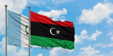 Guatemala ve Libya bayrağı birlikte beyaz bulutlu mavi gökyüzüne karşı rüzgarsal sallayarak. Diplomasi kavramı, uluslararası ilişkiler.