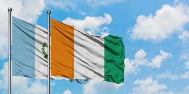 Guatemala ve Fildişi Sahili bayrağı birlikte beyaz bulutlu mavi gökyüzüne karşı rüzgarda sallayarak. Diplomasi kavramı, uluslararası ilişkiler.