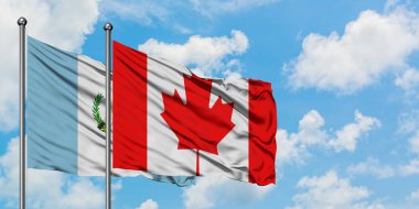 Guatemala ve Kanada bayrağı birlikte beyaz bulutlu mavi gökyüzüne karşı rüzgarda sallayarak. Diplomasi kavramı, uluslararası ilişkiler.