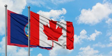 Guam ve Kanada bayrağı birlikte beyaz bulutlu mavi gökyüzüne karşı rüzgarda sallayarak. Diplomasi kavramı, uluslararası ilişkiler.