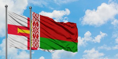 Guernsey ve Beyaz Rusya bayrağı birlikte beyaz bulutlu mavi gökyüzüne karşı rüzgarda sallayarak. Diplomasi kavramı, uluslararası ilişkiler.