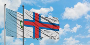 Guatemala ve Faroe Adaları bayrağı birlikte beyaz bulutlu mavi gökyüzüne karşı rüzgarda sallayarak. Diplomasi kavramı, uluslararası ilişkiler.
