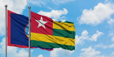 Guam ve Togo bayrağı birlikte beyaz bulutlu mavi gökyüzüne karşı rüzgarda sallayarak. Diplomasi kavramı, uluslararası ilişkiler.