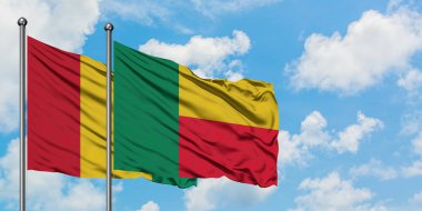 Gine ve Benin bayrağı birlikte beyaz bulutlu mavi gökyüzüne karşı rüzgarda sallayarak. Diplomasi kavramı, uluslararası ilişkiler.