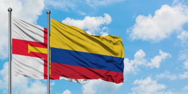 Guernsey ve Kolombiya bayrağı birlikte beyaz bulutlu mavi gökyüzüne karşı rüzgarda sallayarak. Diplomasi kavramı, uluslararası ilişkiler.