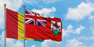 Gine ve Bermuda bayrağı birlikte beyaz bulutlu mavi gökyüzüne karşı rüzgarda sallayarak. Diplomasi kavramı, uluslararası ilişkiler.