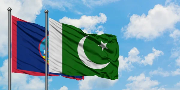 Bandera de Guam y Pakistán ondeando en el viento contra el cielo azul nublado blanco juntos. Concepto diplomático, relaciones internacionales . — Foto de Stock