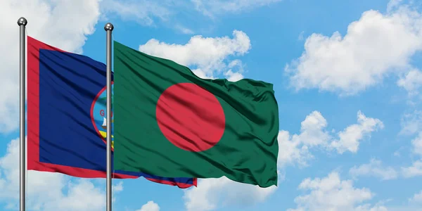 Bandera de Guam y Bangladesh ondeando en el viento contra el cielo azul nublado blanco juntos. Concepto diplomático, relaciones internacionales . — Foto de Stock