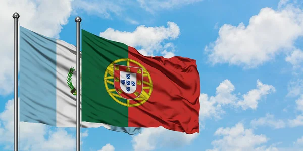 Guatemala och Portugal flagga vinka i vinden mot vit grumlig blå himmel tillsammans. Diplomatisk koncept, internationella relationer. — Stockfoto