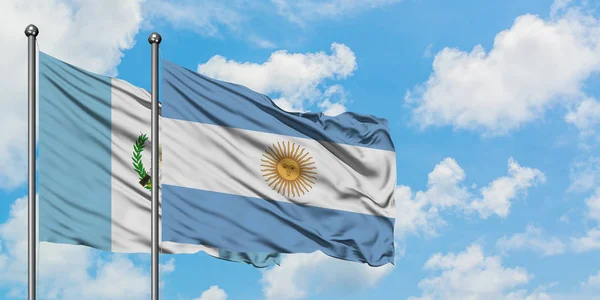 Bandera de Guatemala y Argentina ondeando en el viento contra el cielo azul nublado blanco juntos. Concepto diplomático, relaciones internacionales . —  Fotos de Stock