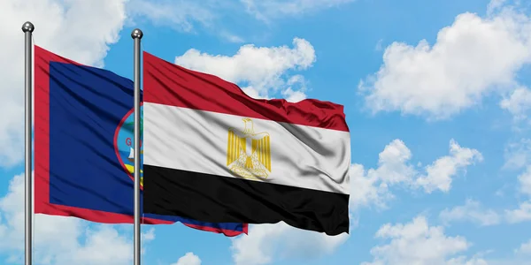 Guam y la bandera de Egipto ondeando en el viento contra el cielo azul nublado blanco juntos. Concepto diplomático, relaciones internacionales . — Foto de Stock