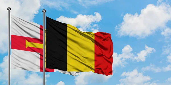 格恩西岛和比利时国旗在风中飘扬，与白云相间的蓝天相会。外交概念、国际关系. — 图库照片