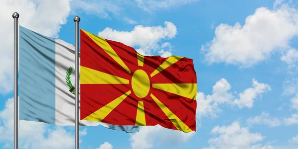Bandera de Guatemala y Macedonia ondeando en el viento contra el cielo azul nublado blanco juntos. Concepto diplomático, relaciones internacionales . — Foto de Stock