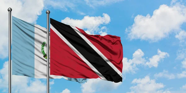 Guatemala ve Trinidad ve Tobago bayrağı birlikte beyaz bulutlu mavi gökyüzüne karşı rüzgarda sallayarak. Diplomasi kavramı, uluslararası ilişkiler. — Stok fotoğraf