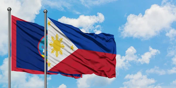 Guam e bandeira das Filipinas agitando no vento contra o céu azul nublado branco juntos. Conceito de diplomacia, relações internacionais . — Fotografia de Stock