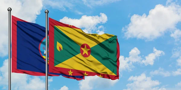 Guam- und Grenada-Flagge wehen gemeinsam im Wind gegen den wolkenverhangenen blauen Himmel. Diplomatie-Konzept, internationale Beziehungen. — Stockfoto