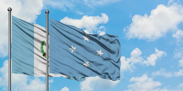 Bandera de Guatemala y Micronesia ondeando en el viento contra el cielo azul nublado blanco juntos. Concepto diplomático, relaciones internacionales . — Foto de Stock