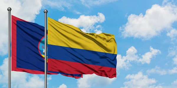 Bandera de Guam y Colombia ondeando en el viento contra el cielo azul nublado blanco juntos. Concepto diplomático, relaciones internacionales . — Foto de Stock