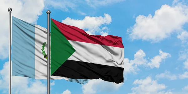 Bandera de Guatemala y Sudán ondeando en el viento contra el cielo azul nublado blanco juntos. Concepto diplomático, relaciones internacionales . — Foto de Stock