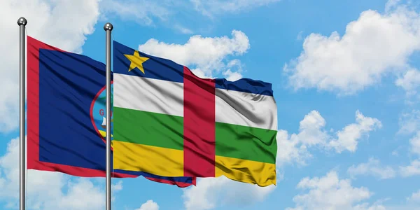 Guam y la bandera de la República Centroafricana ondeando en el viento contra el cielo azul nublado blanco juntos. Concepto diplomático, relaciones internacionales . — Foto de Stock
