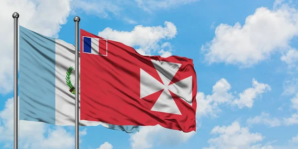 Guatemala y Wallis Y la bandera de Futuna ondeando en el viento contra el cielo azul nublado blanco juntos. Concepto diplomático, relaciones internacionales . — Foto de Stock