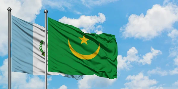 Bandera de Guatemala y Mauritania ondeando en el viento contra el cielo azul nublado blanco juntos. Concepto diplomático, relaciones internacionales . — Foto de Stock