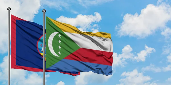 Bandera de Guam y Comoras ondeando en el viento contra el cielo azul nublado blanco juntos. Concepto diplomático, relaciones internacionales . — Foto de Stock