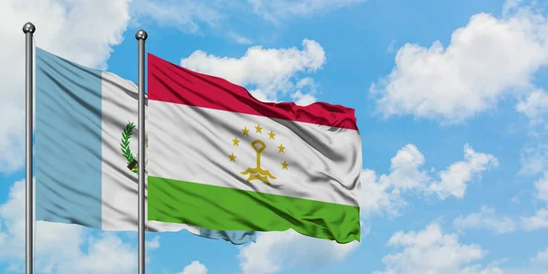 Bandera de Guatemala y Tayikistán ondeando en el viento contra el cielo azul nublado blanco juntos. Concepto diplomático, relaciones internacionales . — Foto de Stock
