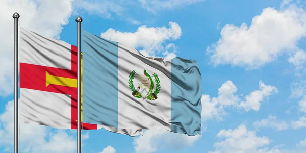 Guernsey ve Guatemala bayrağı birlikte beyaz bulutlu mavi gökyüzüne karşı rüzgarda sallayarak. Diplomasi kavramı, uluslararası ilişkiler. — Stok fotoğraf