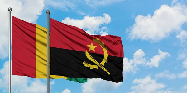 Guinea and Angola flag waving in the wind against white cloudy blue sky together. Diplomacy concept, international relations. — Stock Photo, Image