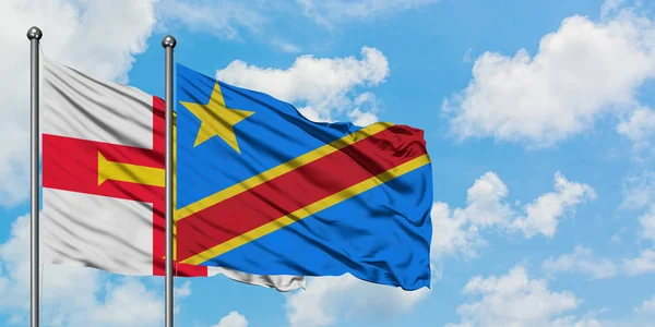 Bandera de Guernsey y Congo ondeando en el viento contra el cielo azul nublado blanco juntos. Concepto diplomático, relaciones internacionales . — Foto de Stock