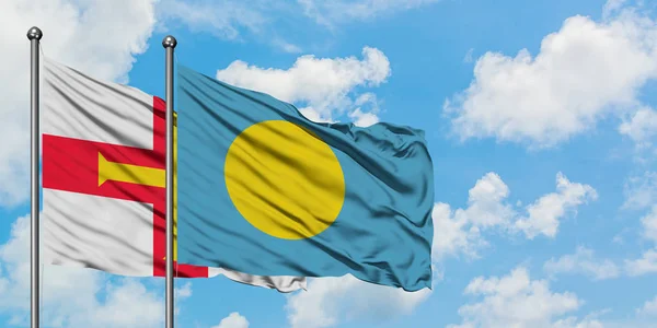 Bandera de Guernsey y Palau ondeando en el viento contra el cielo azul nublado blanco juntos. Concepto diplomático, relaciones internacionales . — Foto de Stock