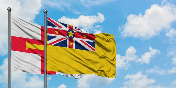 根西岛和纽埃旗在风中飘扬，与白云相间的蓝天相一起。外交概念、国际关系. — 图库照片