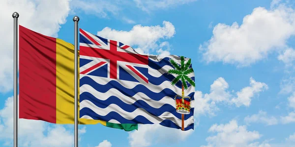 Bandera de Guinea y del Territorio Británico del Océano Índico ondeando en el viento contra el cielo azul nublado blanco juntos. Concepto diplomático, relaciones internacionales . — Foto de Stock