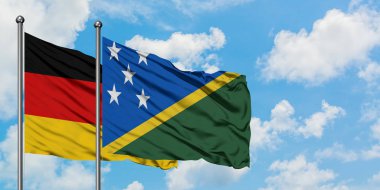 Almanya ve Solomon Adaları bayrağı birlikte beyaz bulutlu mavi gökyüzüne karşı rüzgarsal sallayarak. Diplomasi kavramı, uluslararası ilişkiler.