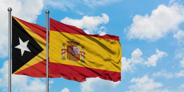 Doğu Timor ve İspanya bayrağı birlikte beyaz bulutlu mavi gökyüzüne karşı rüzgarsal sallayarak. Diplomasi kavramı, uluslararası ilişkiler.