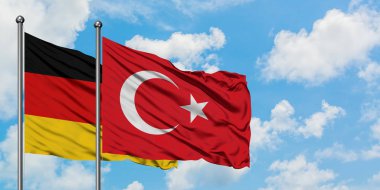 Almanya ve Türkiye bayrağı havada sallayarak beyaz bulutlu mavi gökyüzüne karşı birlikte. Diplomasi kavramı, uluslararası ilişkiler.