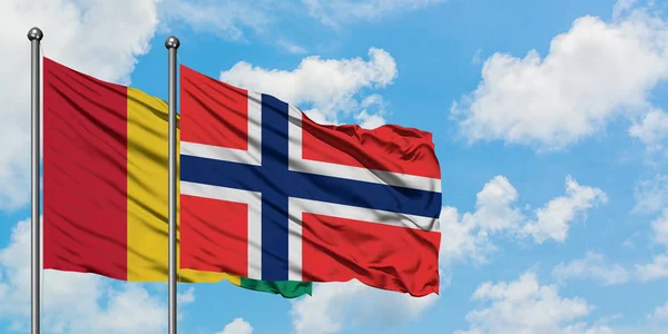 Bandera de Guinea y Bouvet Islands ondeando en el viento contra el cielo azul nublado blanco juntos. Concepto diplomático, relaciones internacionales . — Foto de Stock