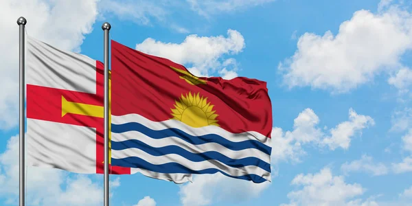 Bandera de Guernsey y Kiribati ondeando en el viento contra el cielo azul nublado blanco juntos. Concepto diplomático, relaciones internacionales . — Foto de Stock