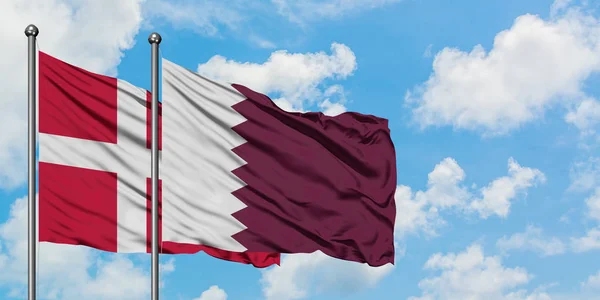 一緒に白い曇り青い空に対して風に手を振るデンマークとカタールの旗。外交概念、国際関係. — ストック写真