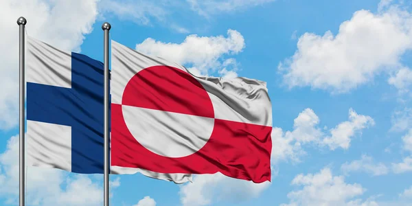 핀란드와 그린란드 국기가 하얀 흐린 푸른 하늘을 배경으로 바람에 흔들리고 있습니다. 외교 개념, 국제 관계. — 스톡 사진