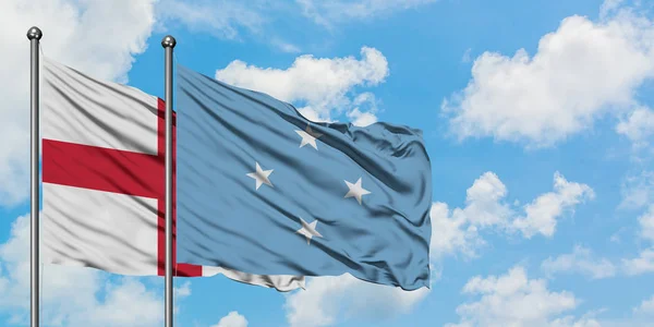 Bandera de Inglaterra y Micronesia ondeando en el viento contra el cielo azul nublado blanco juntos. Concepto diplomático, relaciones internacionales . — Foto de Stock